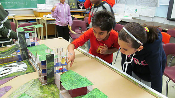 Two kids pointing at sustainable community diorama